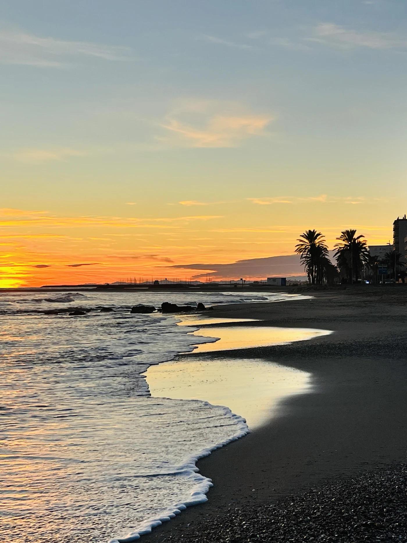 The golden sand and calm water of Platja de Cunit at sunset