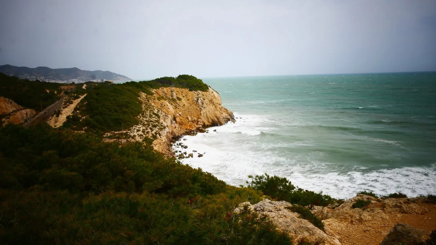 The cliff-top coastal path and railway between Vilanova and Sitges, waves below