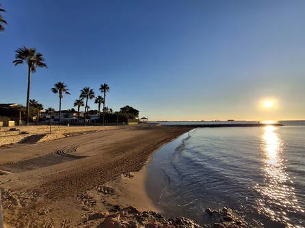 A golden sandy beach at sunset along the coast near Cunit