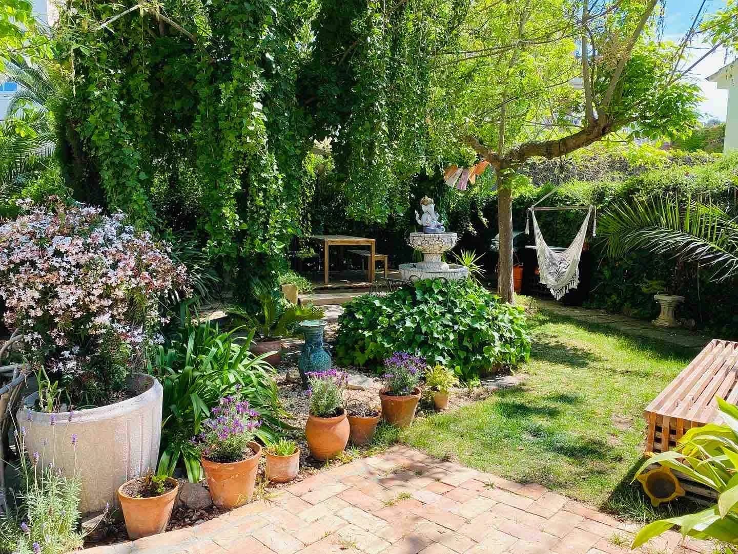 Lush garden at Ikaya Lomlingo with a stone fountain, hammock and potted flowers