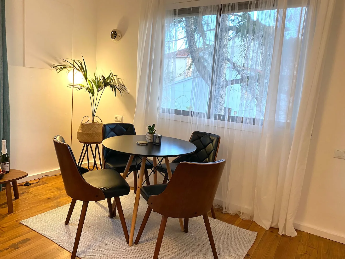 Dining nook with a round black table, leather chairs and a potted palm