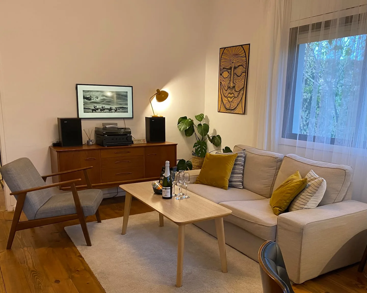 Mid-century sideboard with a record player and tribal art beside a grey armchair