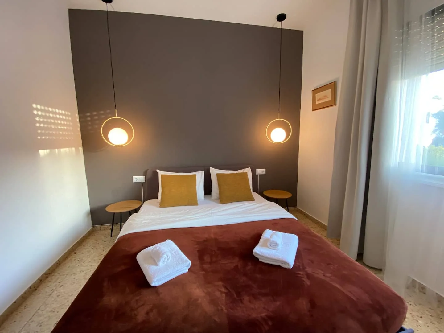 Second bedroom with a grey accent wall, gold pillows and globe pendant lights