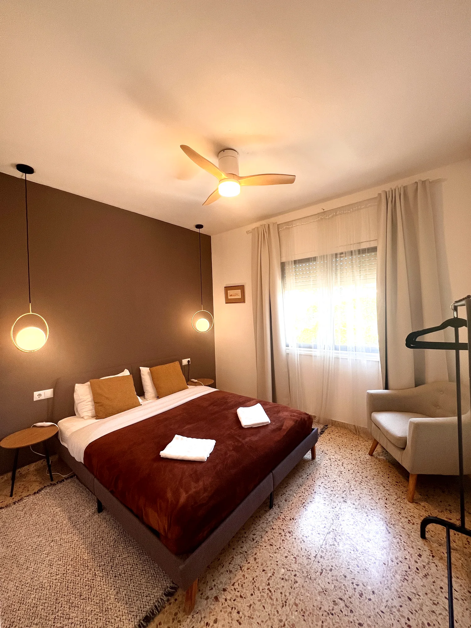 Double bedroom with a grey accent wall, gold pillows and a rust throw